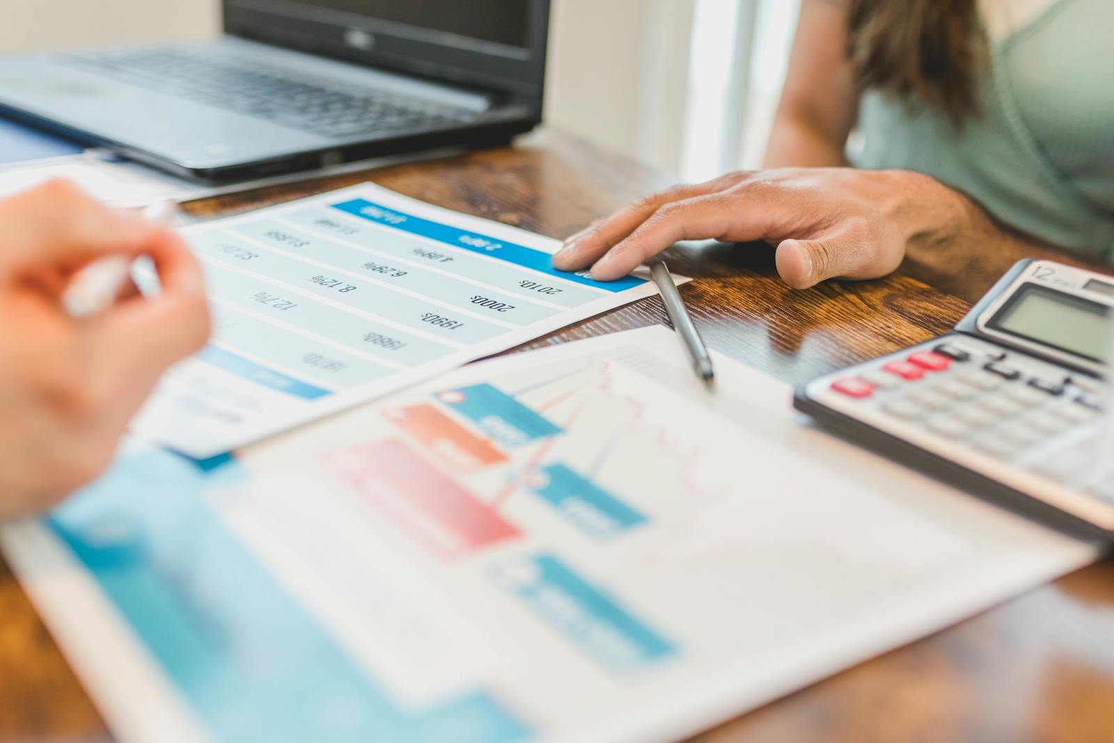 Photo by RDNE Stock project Hands at a desk with financial graphs, calculator, and pen, analyzing business data.